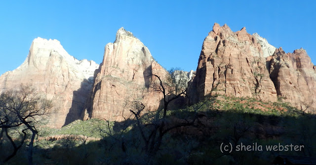 The sun shines on three peaks in the canyon.