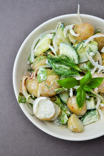 Creamy Vegan Potato Salad with lots of fresh herbs in a white bowl