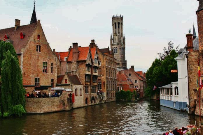 Canal in Bruges with bell tower in the background