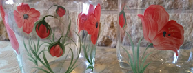 A close up of a glass and jug with poppies on.