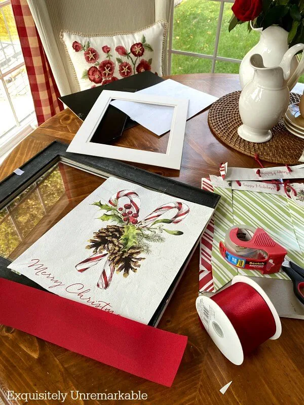 Framing A Gift Bag Supplies ribbon, bag, frame, tape, scissors on table