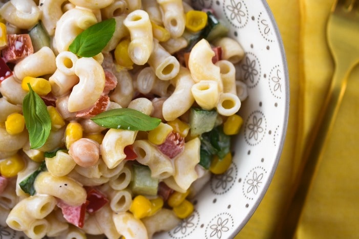 dairy-free macaroni salad close up of macaroni salad topped with fresh basil leaves