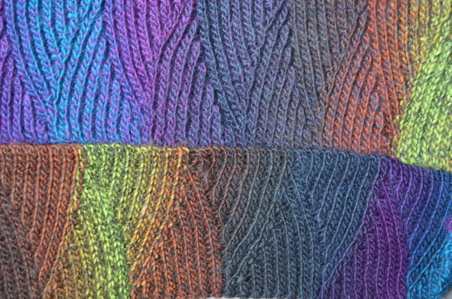 Close up of crocheted scarf made of colour changing yarn: Moda Vera Bouvardia. It blends shades of turquoise, deep blues, purple, grey, charcoal, warm tans and muted lime greens.