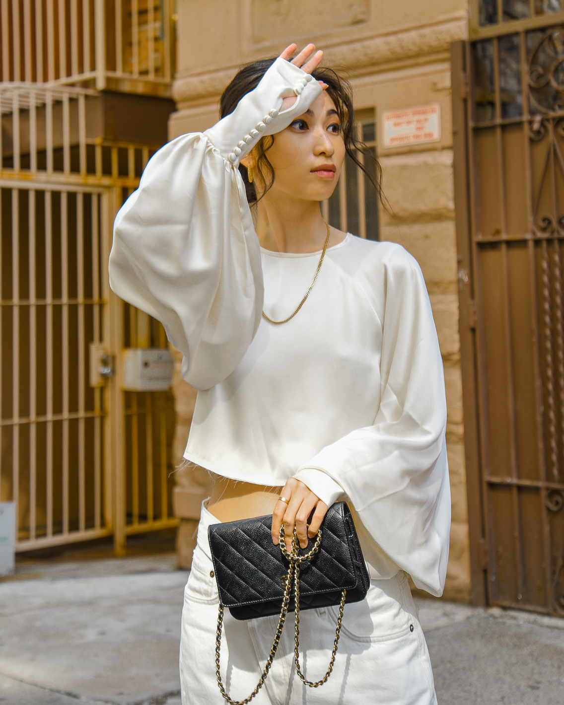 Orseund Iris Drama Cropped Satin Blouse in cream with AgoldE cross-over denim and sneakers casual style in Upper West Side New York City - FOREVERVANNY.com