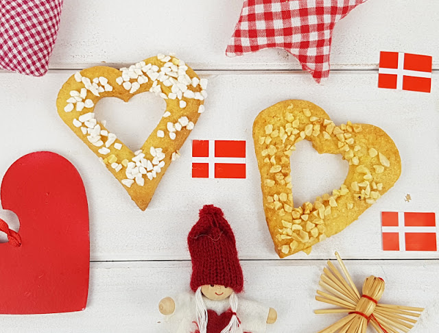 Rezept für Kaerlighedskranse: Das dänische Weihnachtsgebäck mit Herz. die Kränze bzw. runden Kringel und Herzen werden mit Mandeln oder Hagelzucker bestreut und aus Mürbeteig hergestellt.