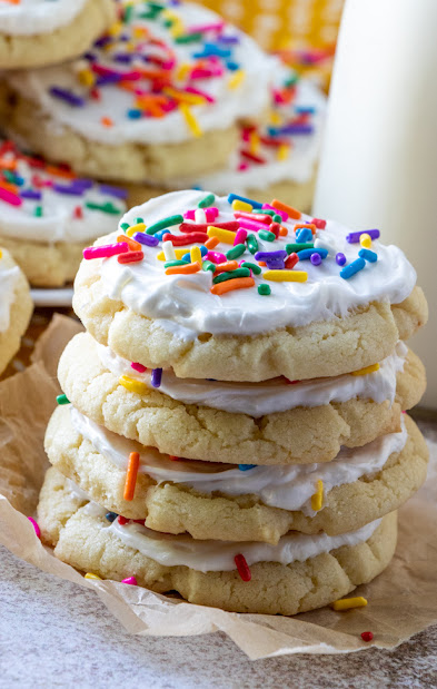 The Best Vanilla Almond Frosted Sugar Cookies stacked with colored sprinkles