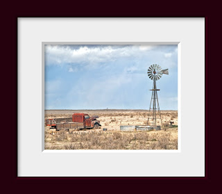 an abandoned old truck resting next to a prairie windmill on the High Plains of Colorado