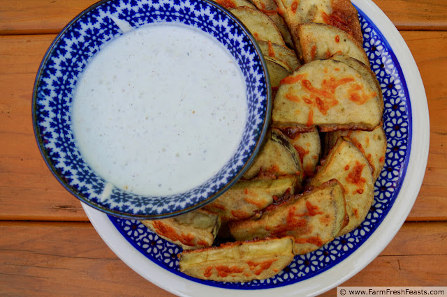 image of a plate of crispy baked eggplant chips with a bowl of spiced yogurt dipping sauce