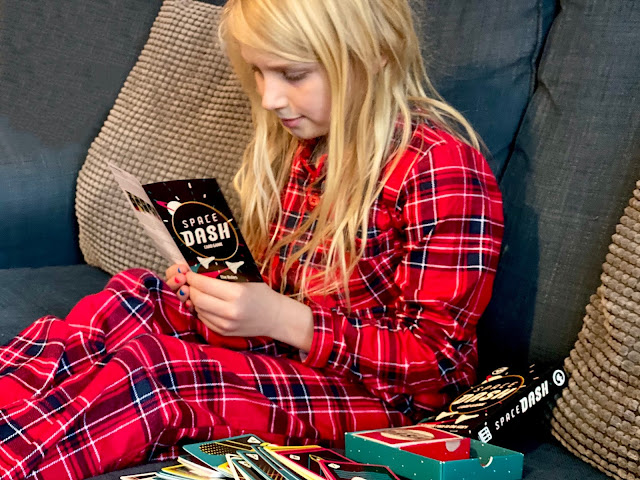 An 8 year old in Christmas PJs reading the instructions for space dash while sitting on a sofa