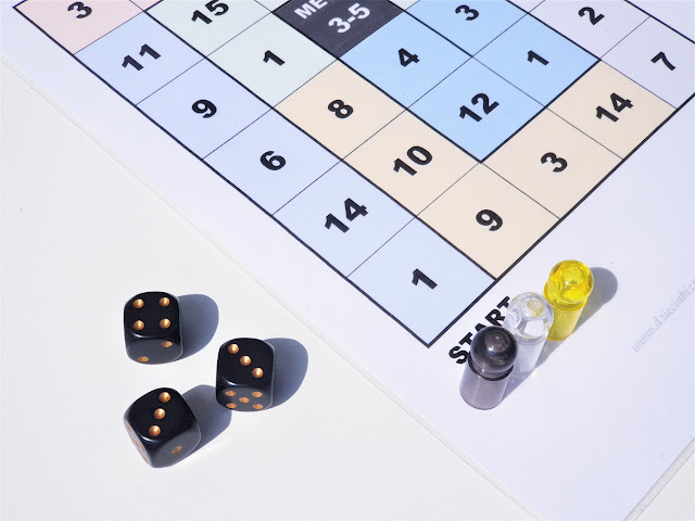 gra wyścig z kostkami gra matematyczna do wydruku, na zdjęciu lewy dolny róg planszy do gry oraz trzy czarne kostki z wyrzuconymi oczkami o wartości 3,3,4