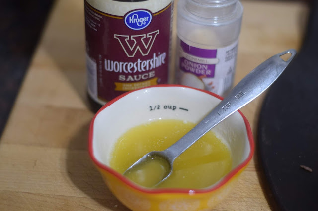 A dish of melted butter with a bottle of Worcestershire sauce and onion powder beside it. 