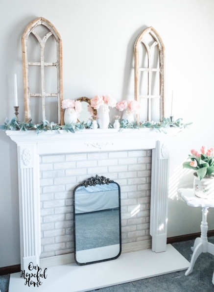 white faux fireplace mantel cathedral arches LED taper candles peonies