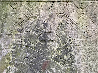 A close up of the grinning skull and crossbones on John Livingstone's Tomb, Edinburgh. The inscription in Latin above the carved skull and crossbones reads ‘MORS PATET, HORA LATET’.  This meaning - ‘Death is sure, the Hour obscure’ or to put it more simply, we are all going to die, but don’t know when.   Photo by Kevin Nosferatu for the Skulferatu Project.