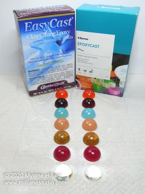 Colourful resin cabochons lined up in front of two boxes of epoxy resin