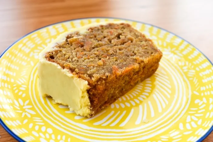 a slice of carrot cake on a yellow side plate