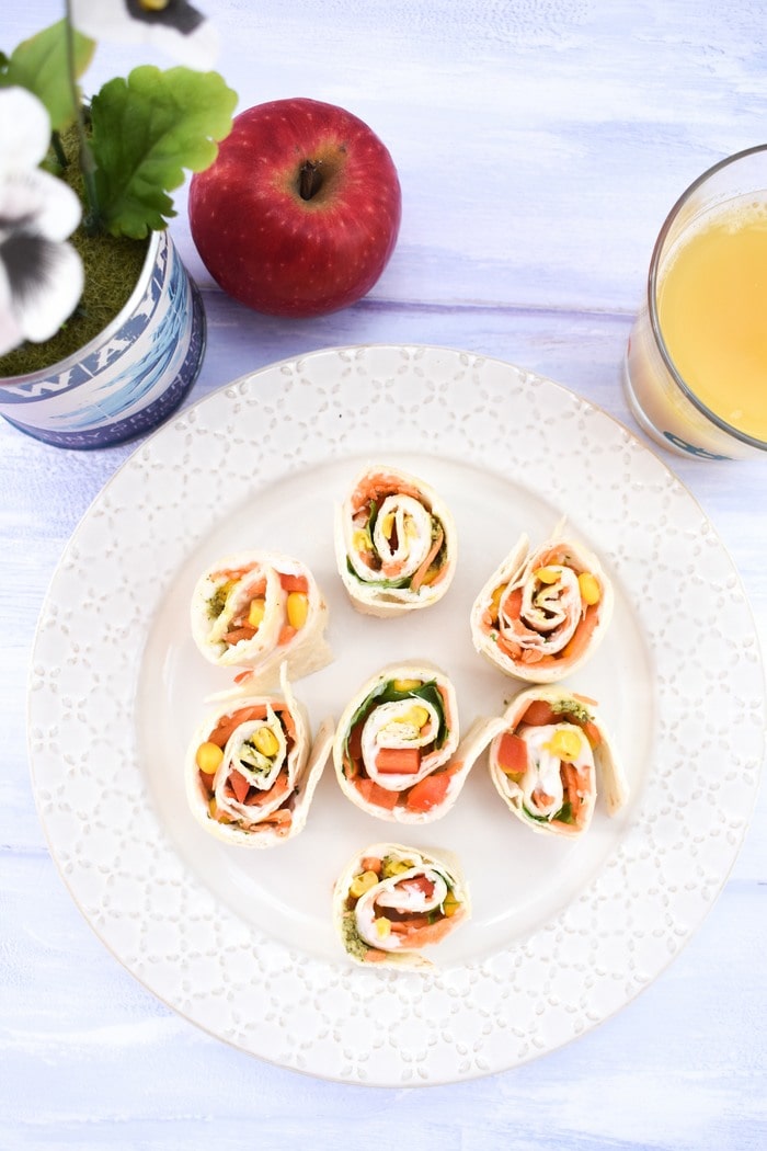 vegan pinwheels Pinwheel sandwiches on a plate next to a tub of daisies and a glass of orange juice