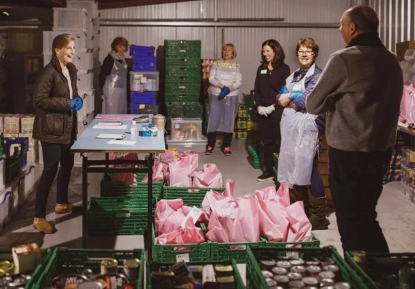 The Countess of Wessex visited the warehouse facility of the Woking Foodbank at Sheerwater. brown coat and pink sweater