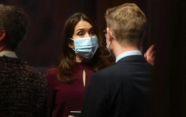 At the award ceremony, Crown Princess Mary wore a burgundy silk mock neck belted top and trousers, and grey cashmere wool long coat