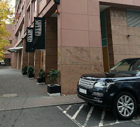 Blick von der Querstraße auf das Gekkos im Frankfurter Hilton. Davor ein schwarzer Range Rover. 