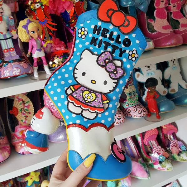 Hello Kitty spotted ankle boot held in hand with shoe shelves in background
