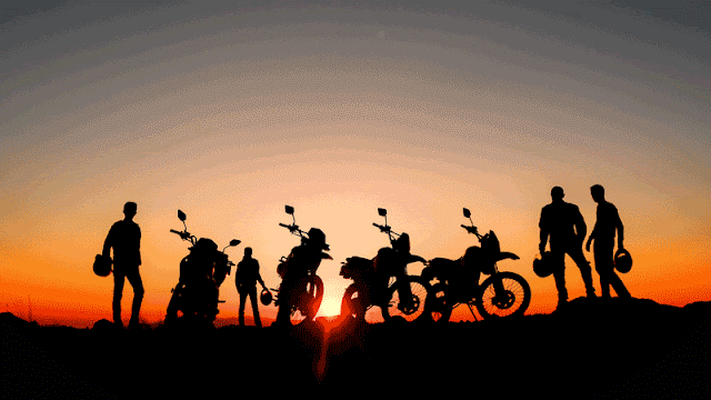 motorcycle riders standing before sunset