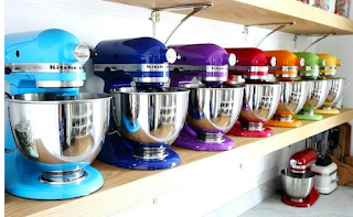 Image shows a shelf full of Kitchenaide mixers in a variety of colours