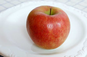 Ein roter Apfel auf einem weißen Teller