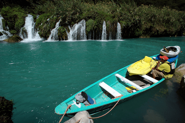 una canoa con turistas cerca a pequeñas cascadas que caen en el río santa maría