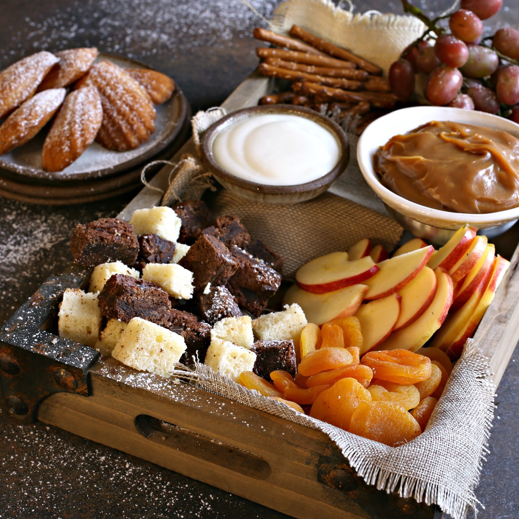 Recipe for creating a dessert treat board with cubes of cake, cookies, fresh fruit, dried fruit and sweet caramel and yogurt dips.