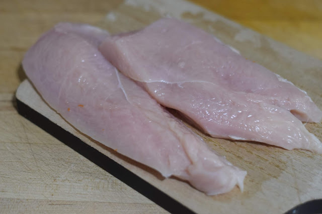 Boneless skinless chicken breasts on a cutting board. 