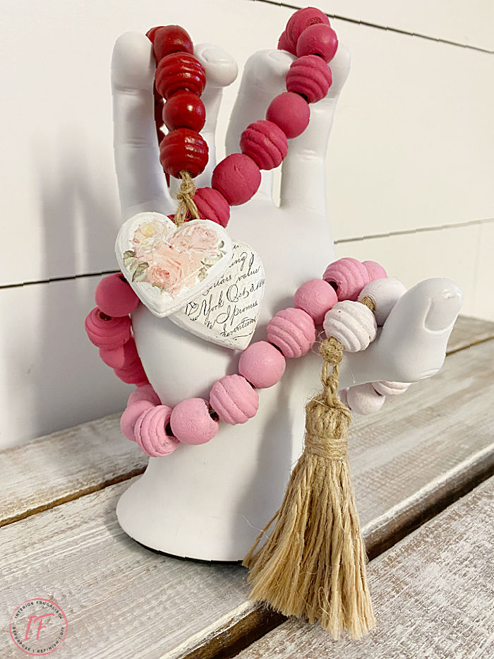 A budget-friendly DIY wooden bead garland painted a pretty gradient pink ombre for Valentine's Day made with a string of dollar store wooden beads.