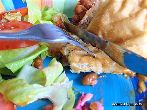 Eating Baked Bean Oven Sub Sandwich with fork and knife.