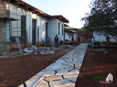 Execução do caminho de pedra Goiás com o revestimento de pedra na fachada da residência, iniciando a execução do paisagismo em residência em Piracaia-SP.