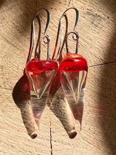 red and clear hollow earrings on wood