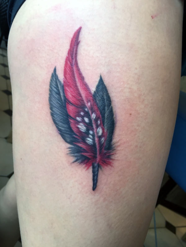 This is a delicate colorful feather tattoo design give a lovely look on the thigh of the girl