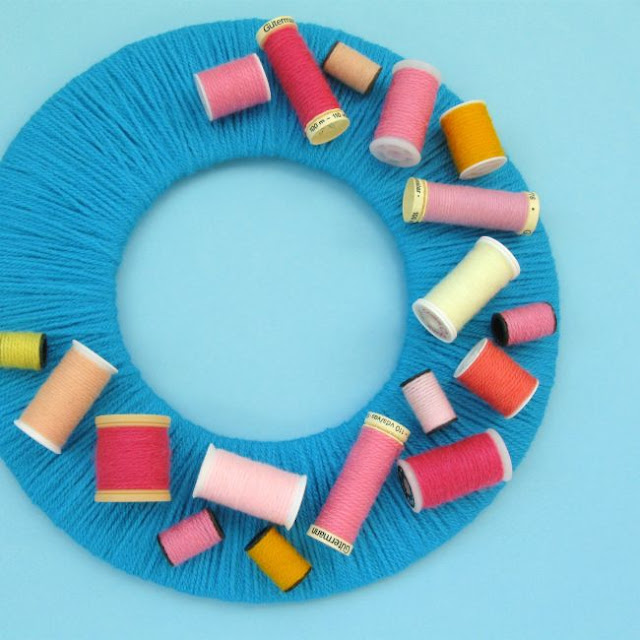 Colourful yarn wreath decorated with upcycled sewing reels