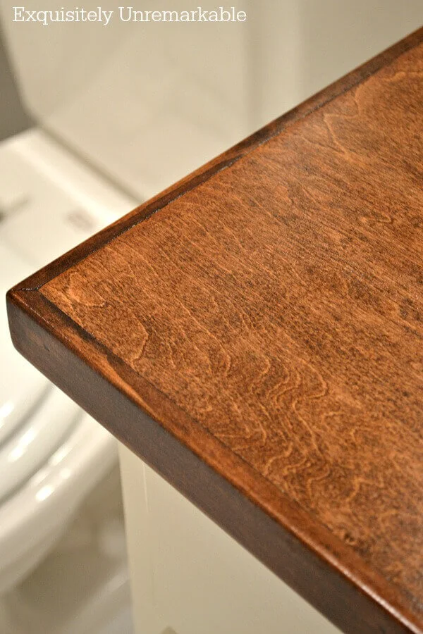 The corner of a stained wooden countertop in a bathroom