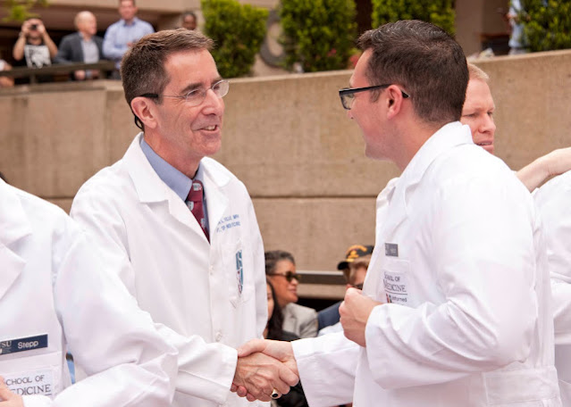 Dr. Kellermann shakes hands in a white lab coat.