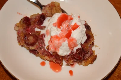 Serving plate of strawberry spoon bread topped with vanilla whipped cream.