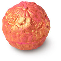 A orange-gold coloured spherical ridged bath bomb coated in gold lustre on a bright background