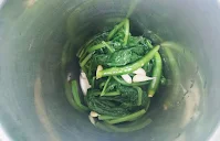 Blanched spinach (palak) garlic and green chili in a grinder for Palak Paneer recipe