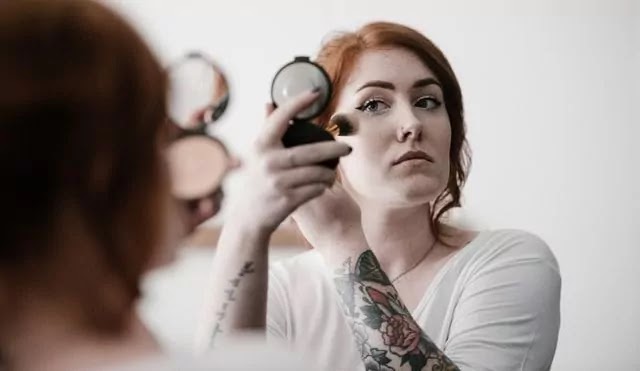 Woman applying makeup near mirror in dressing room