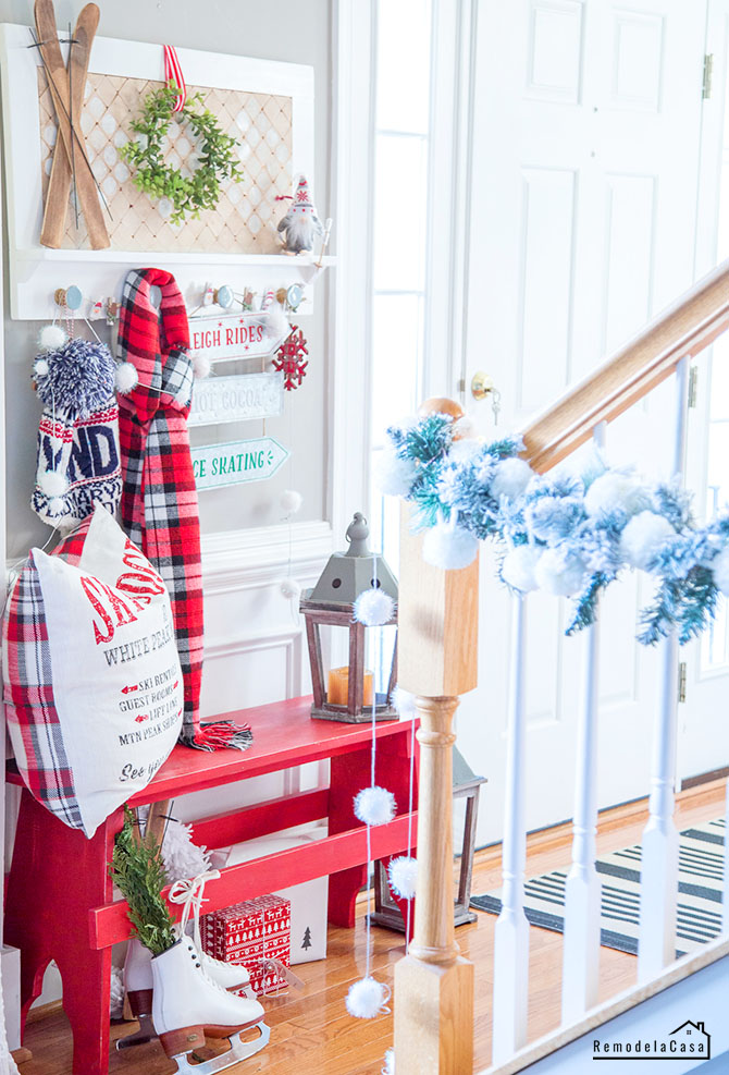 red, white and green holiday decor in the foyer with red bench