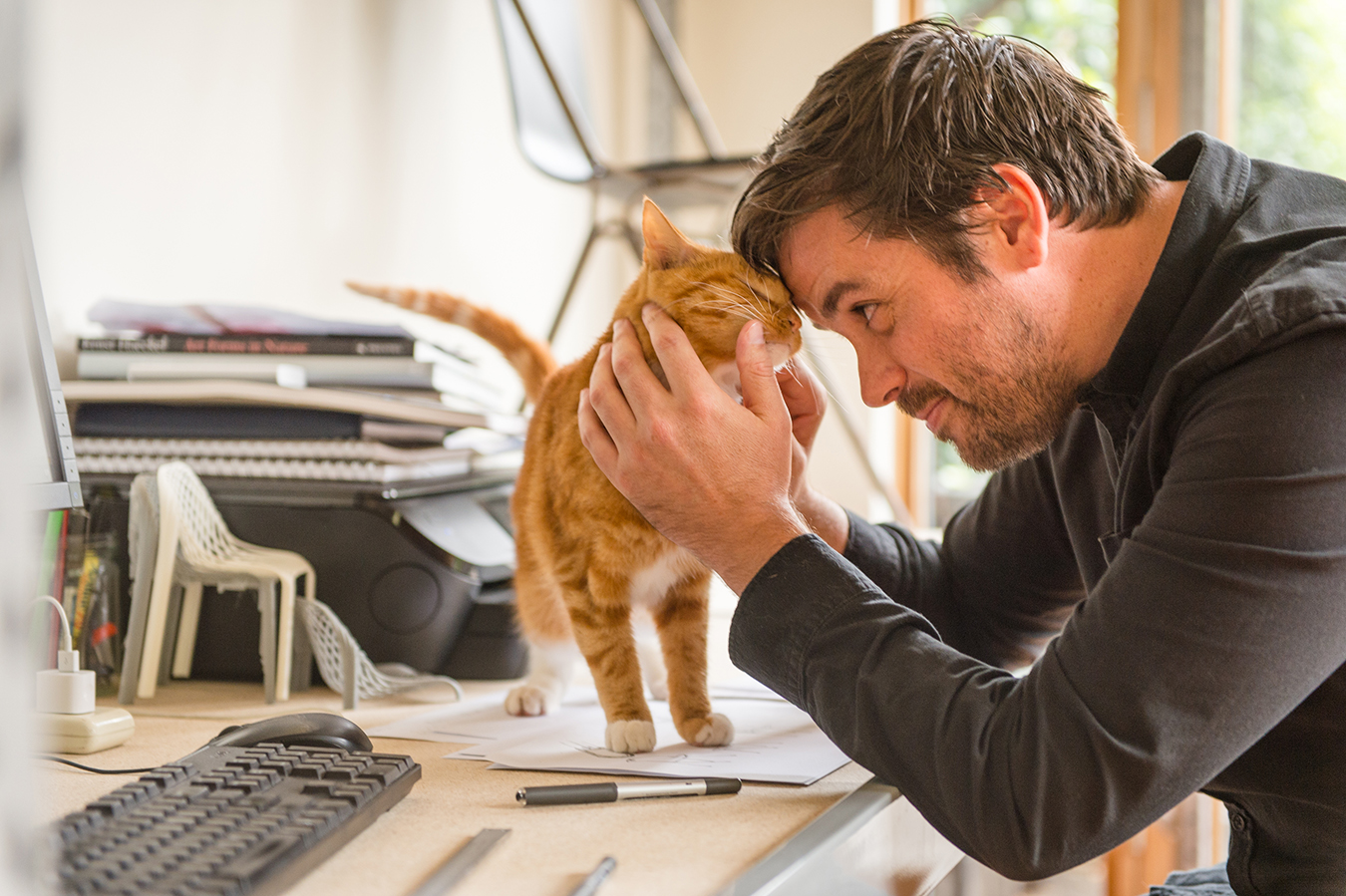 International-Cat-Day-2019-Photo-PETstock-Man-pets-his-ginger-cat-on-his-desk.jpg