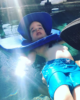 Austin in the swimming pool with a neck float and hat on