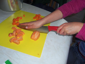 child chopping veg for soup