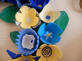 close up of flowers on blue and yellow egg carton wreath