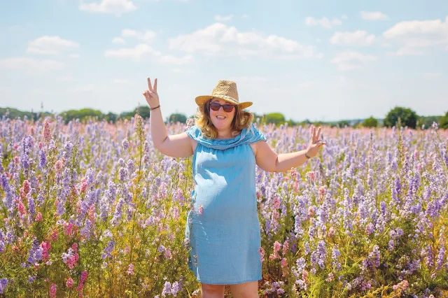 Attractive pregnant woman posing in front of colourful flowers at the confetti flower fields