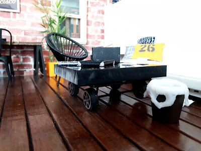 Close up view of a one twelfth scale modern miniature trolley coffee table with a large black slab on the top.