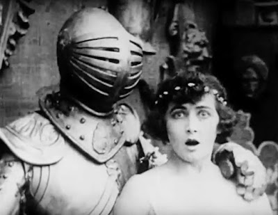 Charley Chase, hiding in a suit off armor, startled Mae Busch in "Love in Armor" (1915)